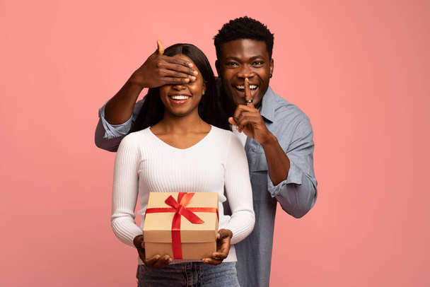 Black millennial couple with gift box on pink background - Photo, Image