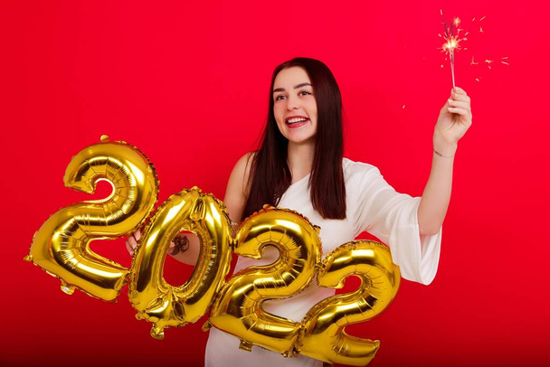 Christmas Holiday Concert - a young smiling woman in a white dress holding the numbers 2022 and sparklers - Фото, зображення