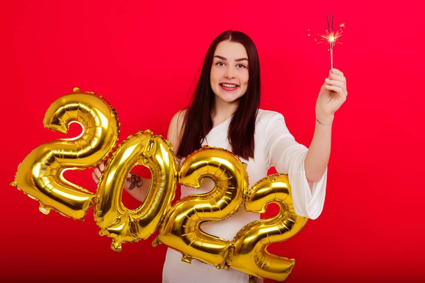 Christmas Holiday Concert - a young smiling woman in a white dress holding the numbers 2022 and sparklers - Фото, зображення