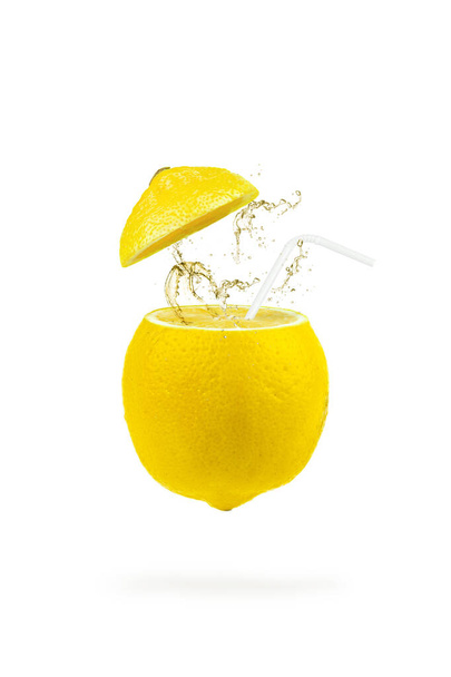 Summer refreshing drink cocktail. Levitation of lemon slices with a straw and splash on white background. Levitation of freshly cut lemon, vertical, closeup - Photo, Image