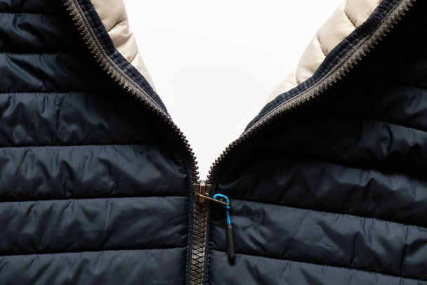 veste d'hiver chaude bleue avec une serrure au milieu comme fond, vêtements, une serrure sur des vêtements sur un fond blanc, vêtements d'hiver parfaits, veste bleue gonflée - Photo, image