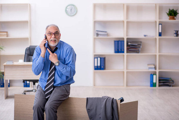 Old male employee unhappy with excessive work in the office - 写真・画像