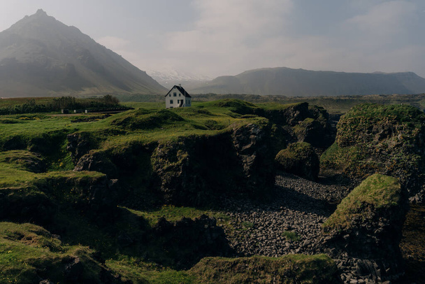 Campo con un villaggio alla base del picco vulcanico di Gatklettur. . Foto di alta qualità - Foto, immagini