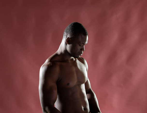 Muscular build black man against pink background. - Φωτογραφία, εικόνα