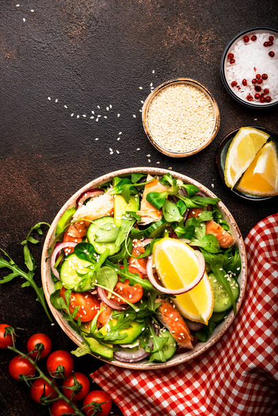 Fresh Salad with chicken, tomatoes, arugula, onion, avocado, sesame seeds and lemon oil dressing. Healthy food. Top view. Brown table - Foto, Imagem