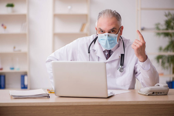 Stary lekarz pracujący w klinice podczas pandemii - Zdjęcie, obraz