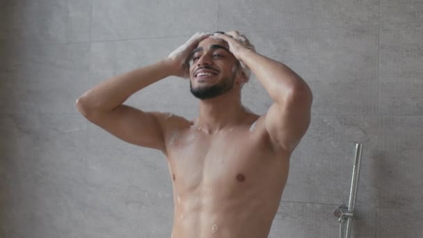 Zoom in portret van jonge gelukkig naakt midden oosten kerel onder de douche, het wassen van zijn haar, genieten van grote shampoo voor mannen - Video