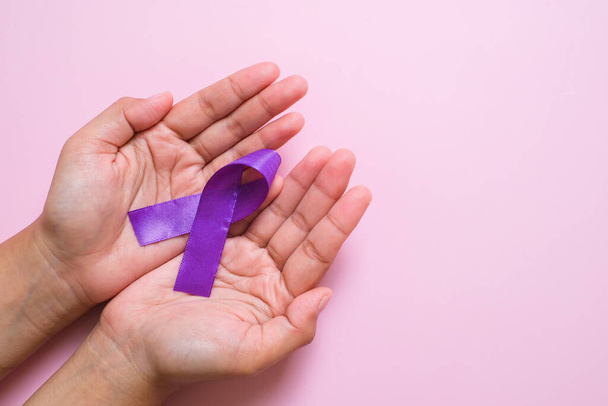 Manos sosteniendo cintas púrpuras concepto del día mundial del cáncer, enfermedad de Alzheimer, cáncer de páncreas, conciencia de epilepsia, conciencia de violencia doméstica, conciencia de fibromialgia - Foto, Imagen