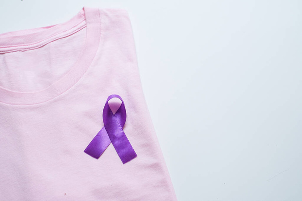 Фіолетова стрічка як символ Всесвітнього дня раку над рожевим фоном. - Фото, зображення