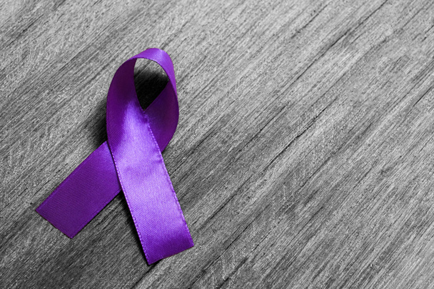 Cinta púrpura como símbolo del Día Mundial del Cáncer sobre textura de madera en blanco y negro - Foto, imagen