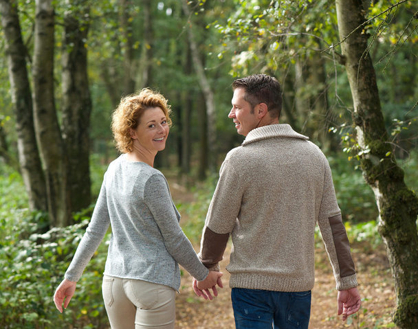 Happy couple holding hands and walking in the forest - 写真・画像
