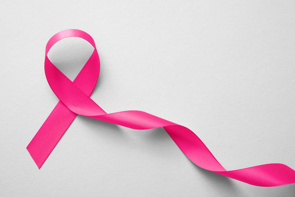 Pink ribbon on white background, top view. Breast cancer awareness concept - Фото, зображення