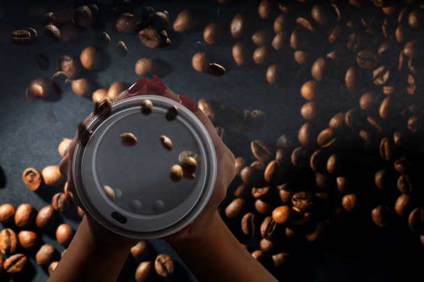 Coffee paper cups with coffee beans on a dark background. Pattern and creative background concept for cafes. - Photo, Image