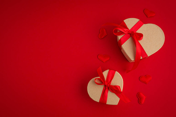 Twee gewikkelde geschenkdozen in hartvorm op rode achtergrond, Sint Valentijnsdag - Foto, afbeelding