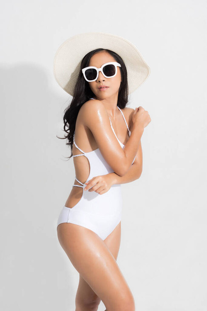 Hermosa mujer en la felicidad con traje de baño blanco vestido gafas de sol blancas en concepto de verano estudio de moda disparar aislado sobre fondo blanco. - Foto, imagen