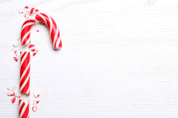 Broken sweet Christmas candy cane on white wooden table, top view. Space for text - Zdjęcie, obraz