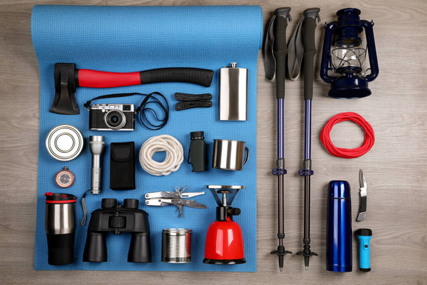 Flat lay composition with different camping equipment on wooden background - Foto, Bild
