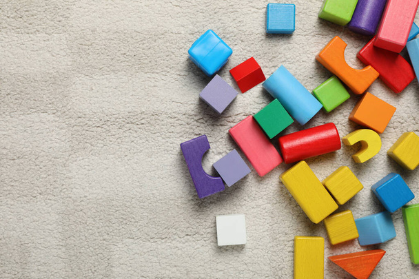 Colorful wooden building blocks on carpet, flat lay. Space for text - Φωτογραφία, εικόνα