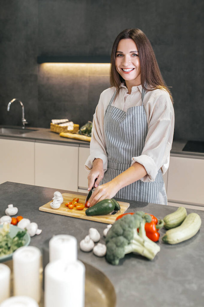 Long-haired young housewife cooking in the kitchen - Foto, Bild