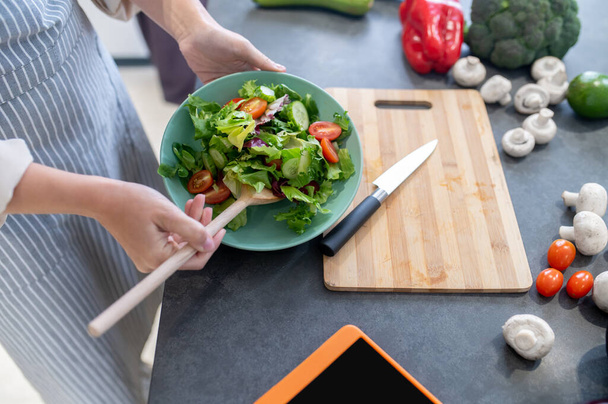 Woman cutting vegetables on a cutting board - Foto, afbeelding