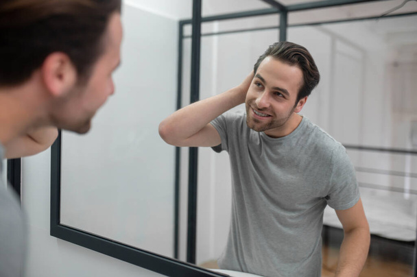 Man near the mirror scrutinizing himself - Foto, afbeelding