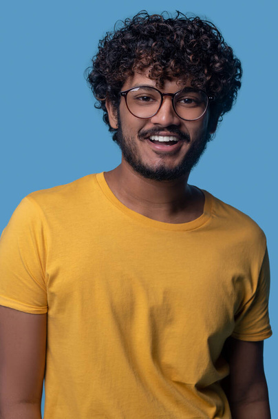 Cheerful young curly-haired man wearing stylish eyeglasses - Фото, зображення