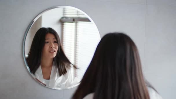 Asiática mujer tocando pelo having split ends problema en cuarto de baño - Metraje, vídeo