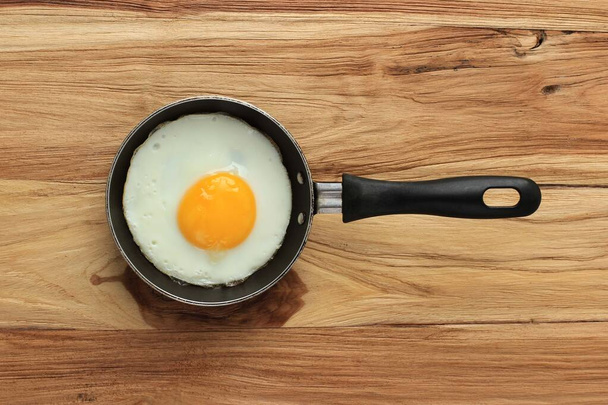 Солнечное яйцо с идеальным круглым желтым яйцом. Вид сверху на деревянный стол - Фото, изображение