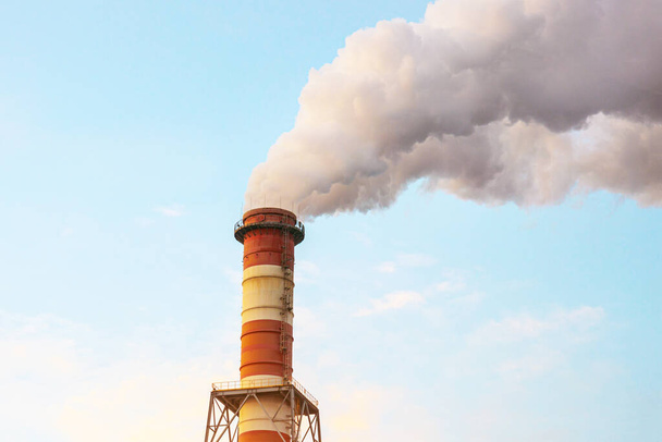Büyük bir fabrika bacasından çıkan dumandan kaynaklanan hava kirliliği. Bacalardan mavi gökyüzüne doğru yakın plan bir duman çıkıyor. Hava kirliliği kavramı, hava emisyonları - Fotoğraf, Görsel