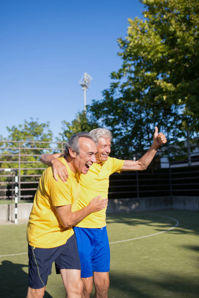 Happy senior men playing football on sunny day - Foto, Imagen