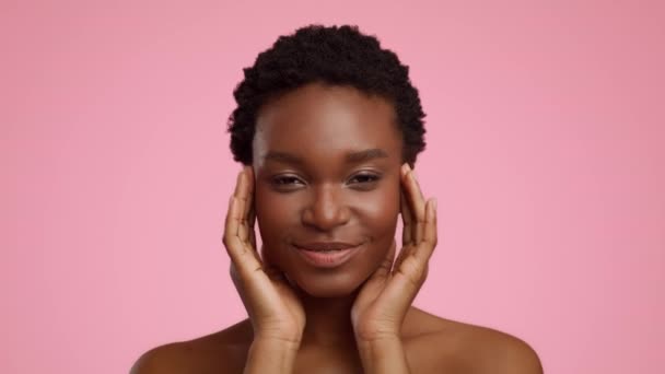 Ontspannen Afro-Amerikaanse vrouw masseren tempels over roze achtergrond - Video