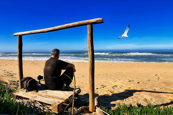 Дорослий чоловік фотографує океан наприкінці осені
 - Фото, зображення