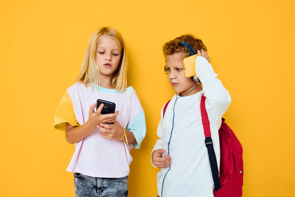 niños escolares con mochilas escolares teléfono entretenimiento comunicación - Foto, Imagen