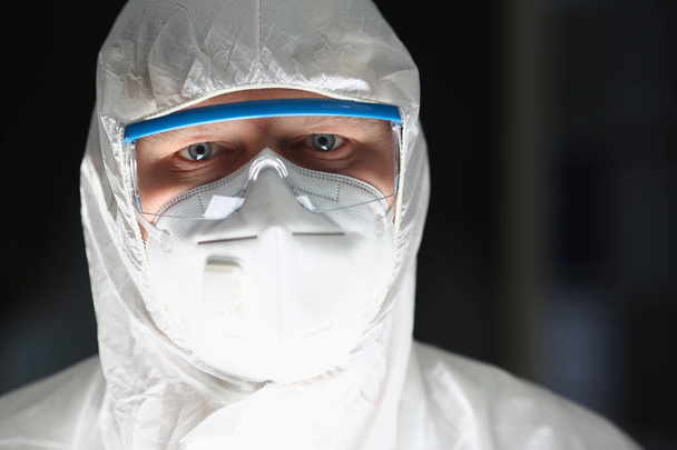 Male lab worker in protective respirator and white coverall, smart scientist - Фото, изображение