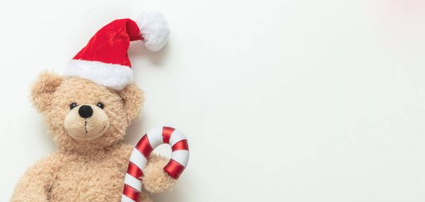 Urso de peluche usando chapéu de Papai Noel no fundo branco, banner, espaço de cópia. Um presente de Natal. Crianças feriados presentes, brinquedos e animais de pelúcia. Feriado cartão de saudação. - Foto, Imagem