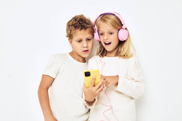 Young cheerful kid headphones with phone entertainment isolated background - Foto, Bild