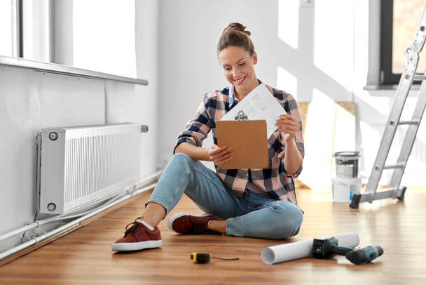 woman with clipboard sitting on floor at home - Photo, Image