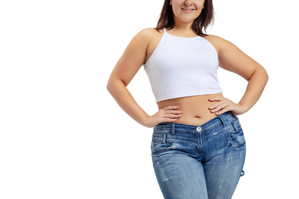 Cropped image of plus-size woman wearing white t-shirt and jeans posing isolated on white studio background. - Fotoğraf, Görsel