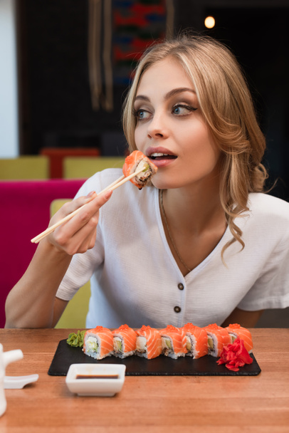 fiatal szőke nő eszik finom tekercsek sushi bár - Fotó, kép