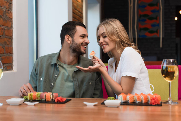 femme gaie nourrir petit ami avec de délicieux sushis pendant la date dans le restaurant - Photo, image