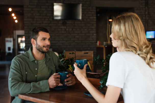 joven hablando con novia borrosa durante la cita en la cafetería - Foto, Imagen