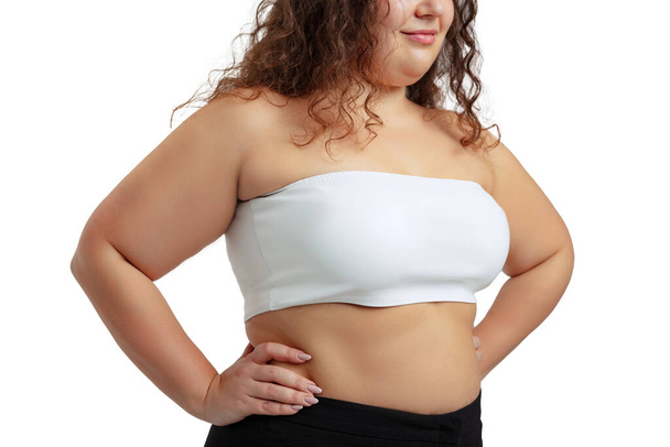 Cropped image of plus-size woman wearing white top and jeans posing isolated on white studio background. - Foto, imagen