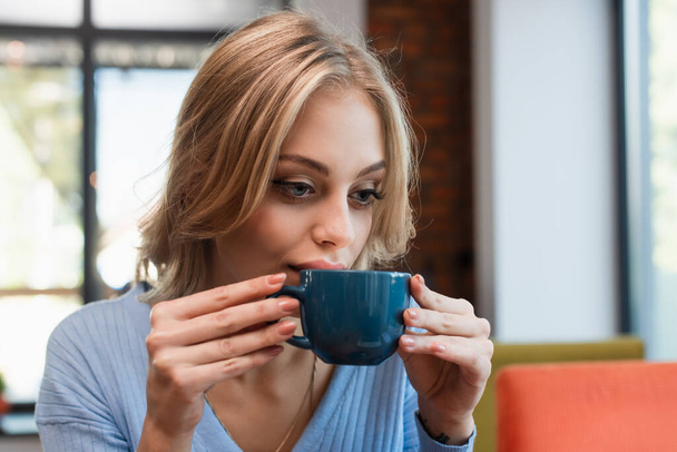 pretty blonde woman drinking coffee in restaurant - Fotoğraf, Görsel