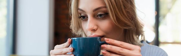 young blonde woman drinking coffee in restaurant, banner - Fotó, kép