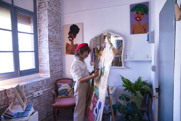Young woman, artist, designer and painter working on one of her works with a black marker inside her studio. Concept painting, drawing, designer, artist, modern. - Foto, Imagem