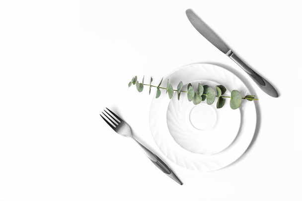 Bahar şatafatlı sofra, restoran menüsü konsepti. Masadaki beyaz tabaklar, gümüş takımlar ve okaliptüs dalları. Yemek için hazırlan. Üst görünüm, düz uzanma. - Fotoğraf, Görsel