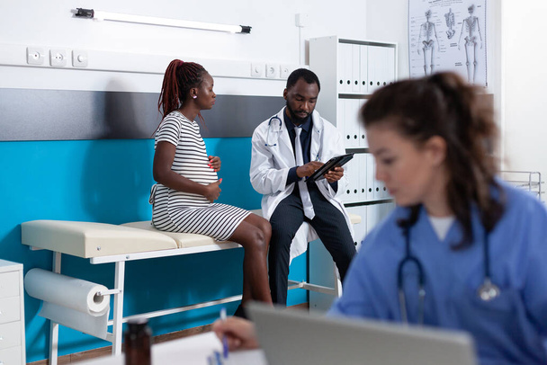 Médico discutiendo con la paciente embarazada sobre la atención médica - Foto, Imagen