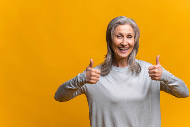 Portrait of cheerful beautiful woman with trendy hairdo engaging smile and showing cool gesture while posing in studio over yellow background. People, happiness, emotions and lifestyle - Foto, immagini
