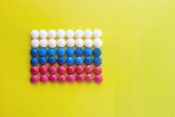 on a yellow background, the tricolor flag of Russia made of round sweets - Fotó, kép