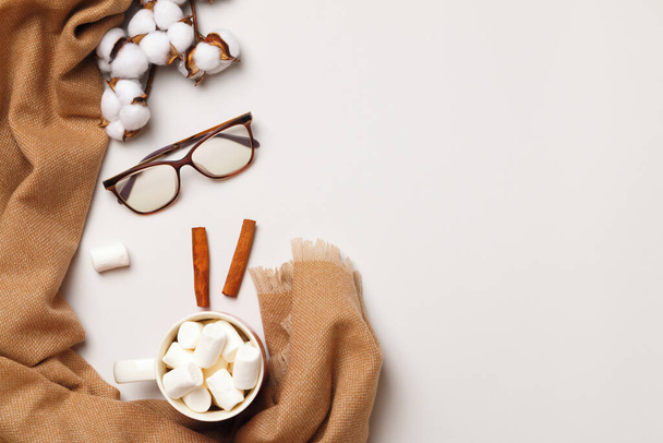 Beige cashmere scarf cup marshmallows cinnamon branch of cotton glasses on a gray background. The concept of winter comfort and coziness. Flat lay top view copy space. - Foto, Imagem